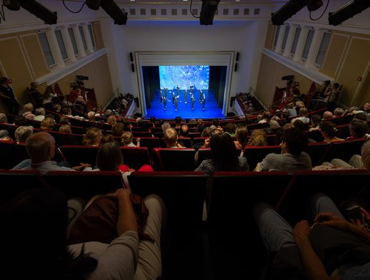 Publikum im Lessingtheater Wolfenbüttel verfolgt eine Tanzaufführung auf einer hellblauen Bühne