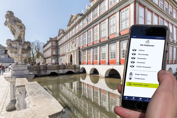Barockes Schloss Wolfenbüttel mit Wassergraben, Brücke und Smartphone mit Touren-App in der Hand