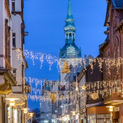 Straßenzug mit Kirchturm, Lichterketten überspannen die Straße