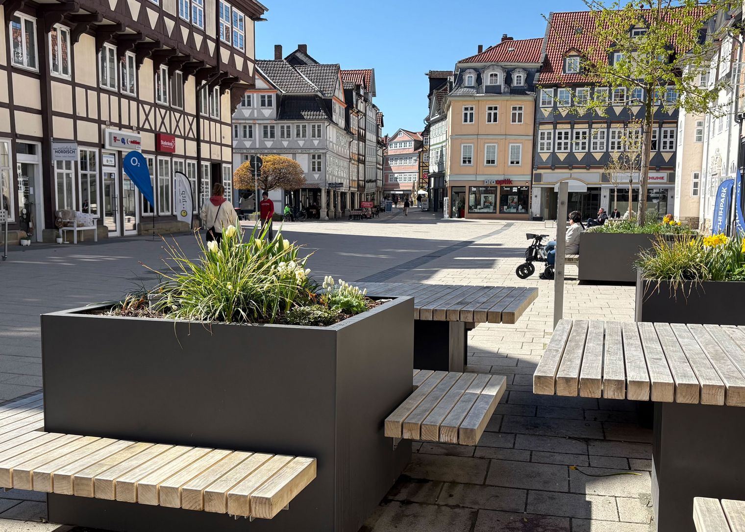 Holzbänke rund um große Blumenkübel, dahinter Fachwerkhäuser
